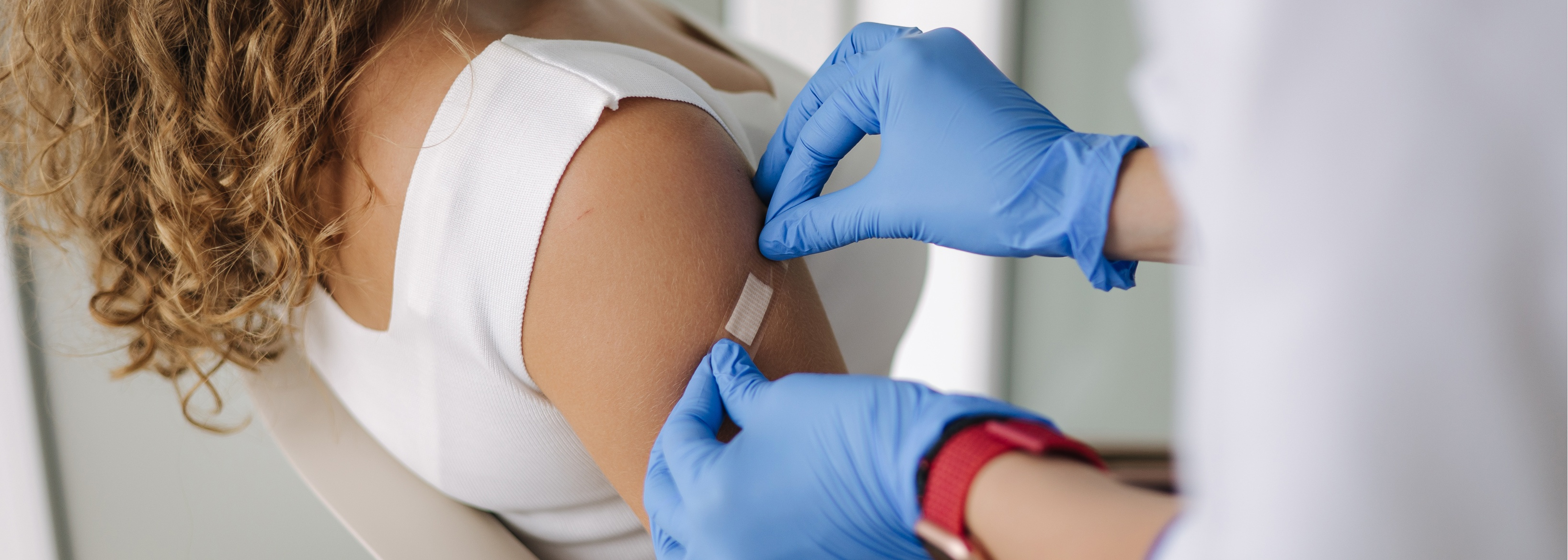 Farmaceutka przykleja plaster pacjentce po szczepieniu