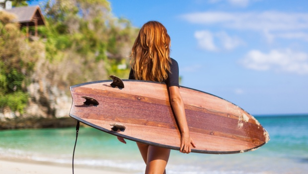 Kobieta trzyma deskę do surfingu wchodząc do wody